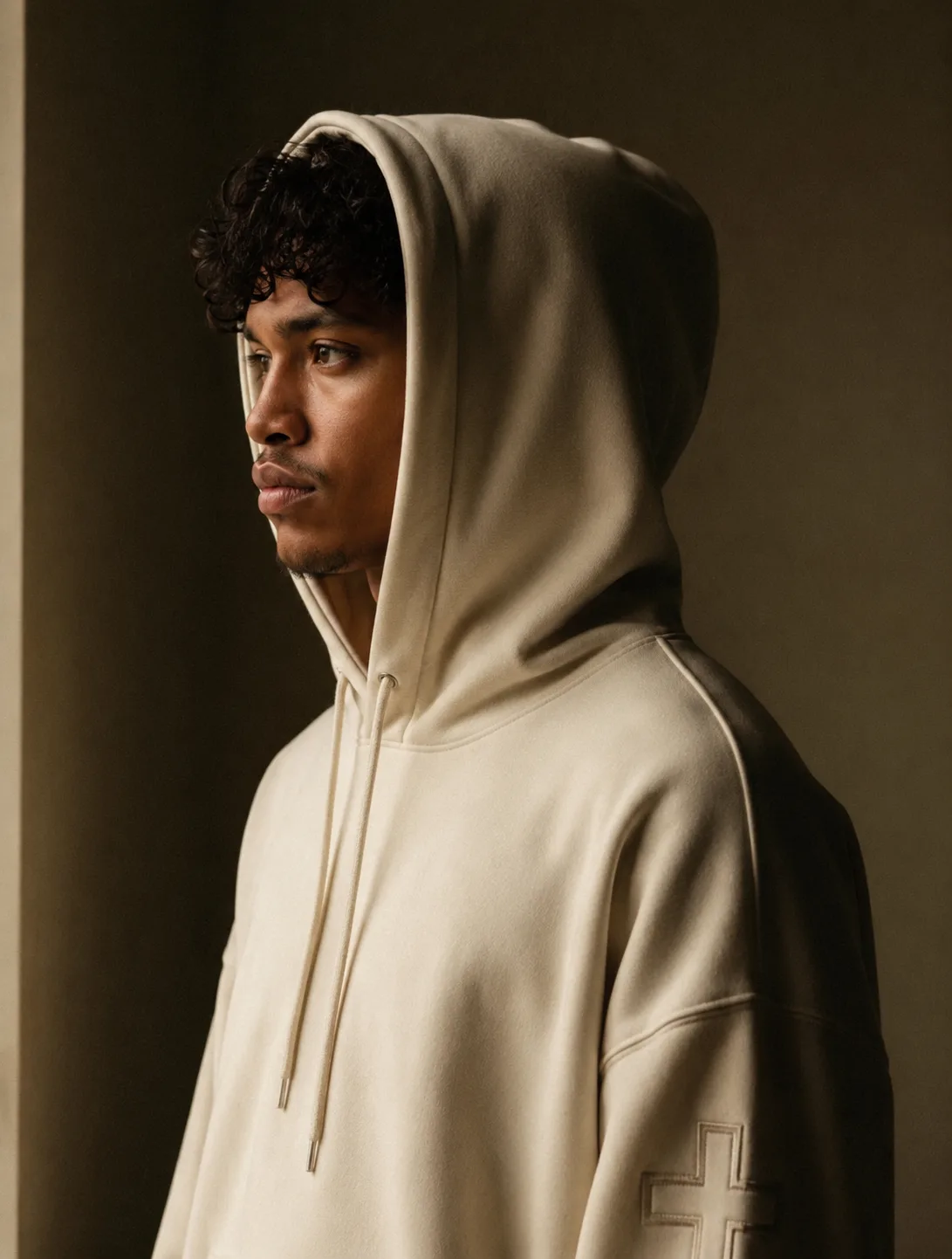 Female model in cream hoodie, profile, soft window light
